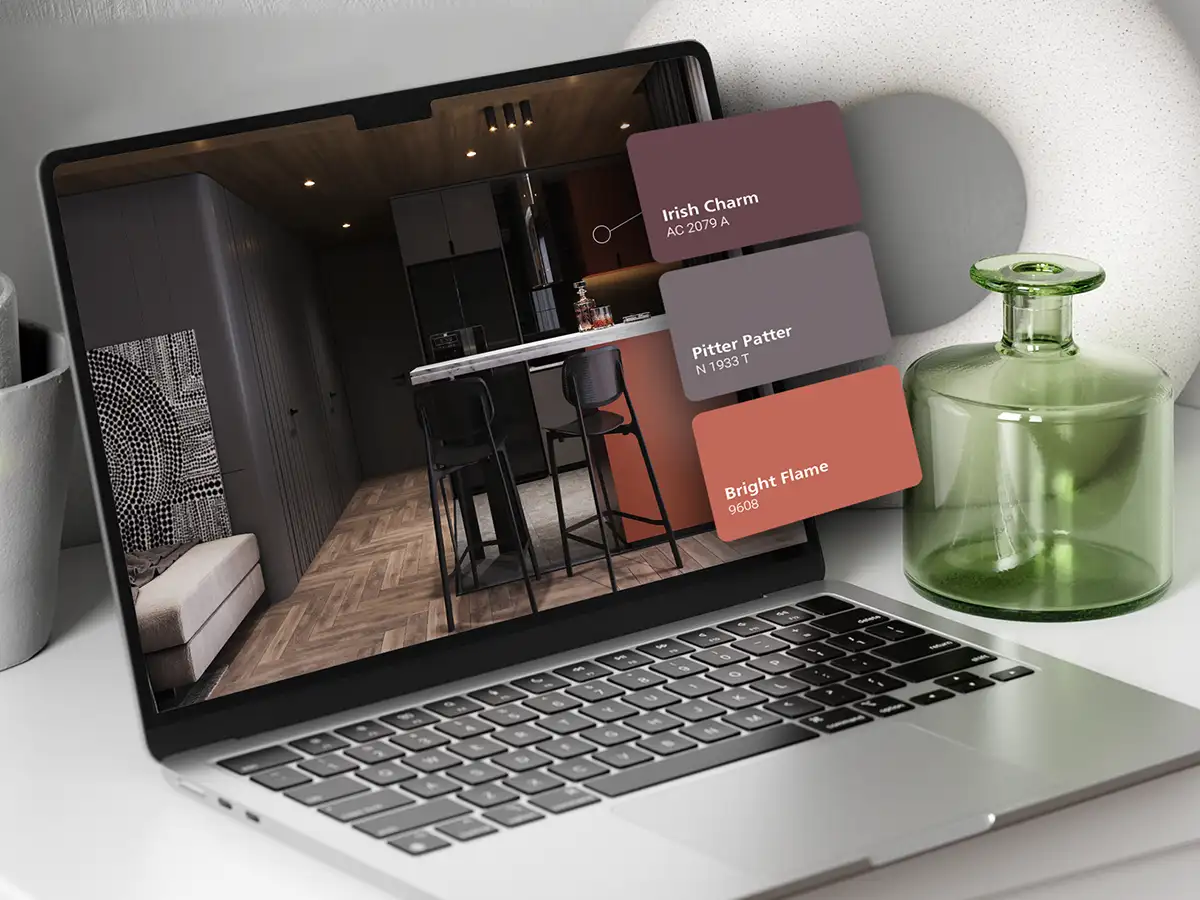 Laptop displaying a modern interior design with Nippon Paint color swatches: Irish Charm (AC 2079 A), Pitter Patter (N 1933 T), and Bright Flame (9608), alongside a stylish green glass vase.
