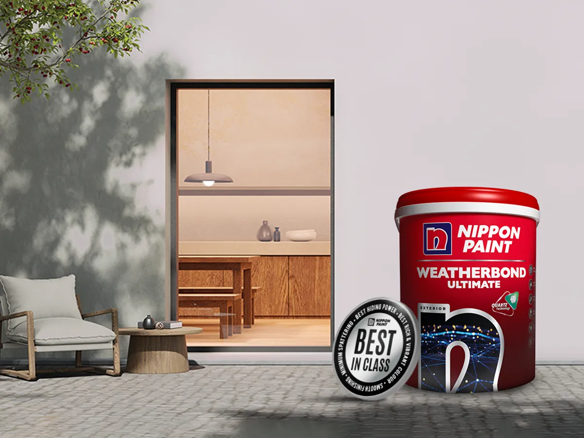 Nippon Paint Weatherbond Ultimate product displayed next to a modern outdoor setting featuring a cozy chair and table, highlighting its durability and aesthetic appeal for exterior applications.