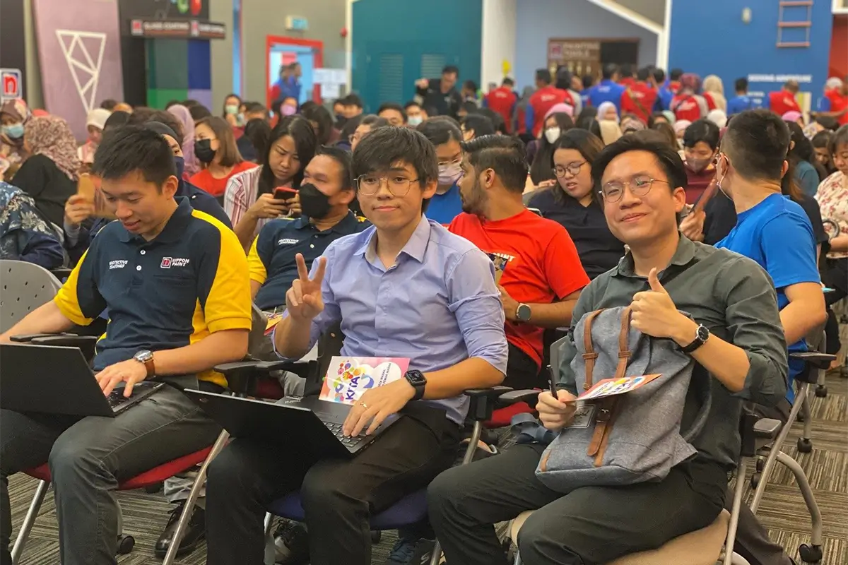 Audience at a Nippon Paint event, featuring participants engaged with laptops and showing enthusiasm, as they gather for a presentation or workshop.