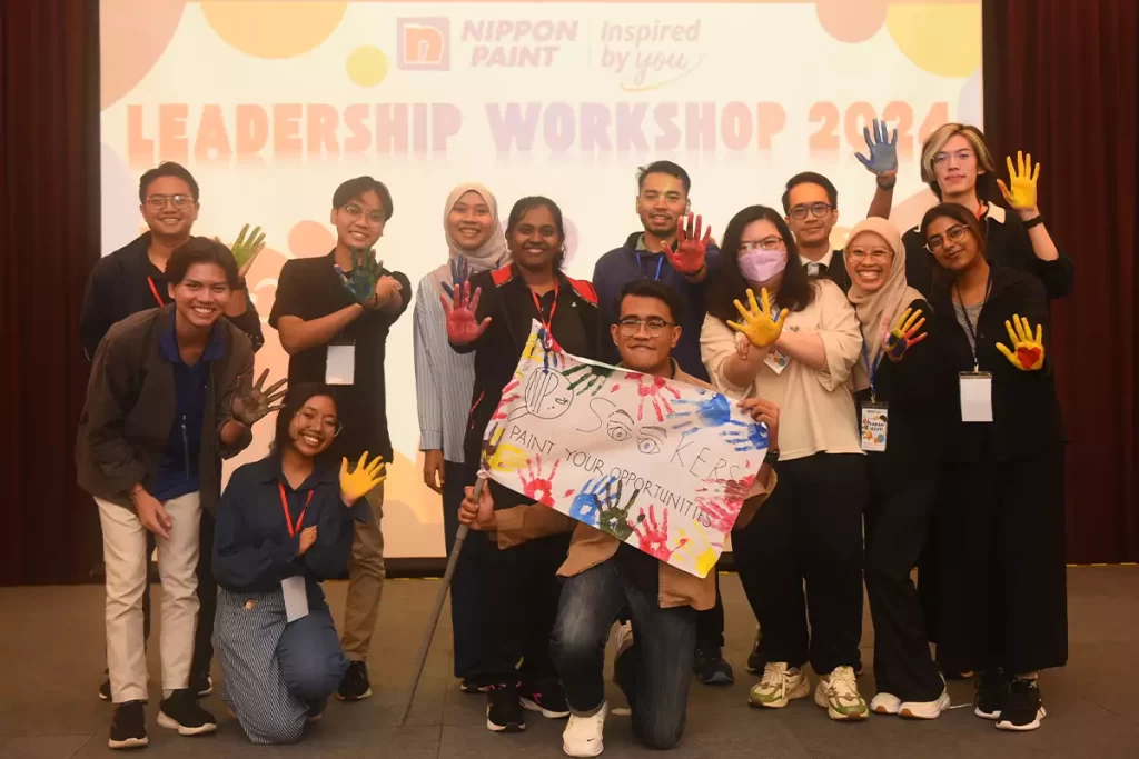 Group photo from the Nippon Paint Leadership Workshop 2024, featuring participants with colorful handprints, showcasing creativity and collaboration. The backdrop highlights the event's theme, "Inspired by You," emphasizing leadership development.