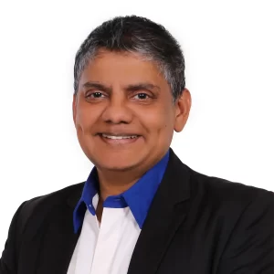 Portrait of a professional man wearing a black suit with a blue shirt, smiling confidently against a white background, representing the innovative spirit of Nippon Paint.
