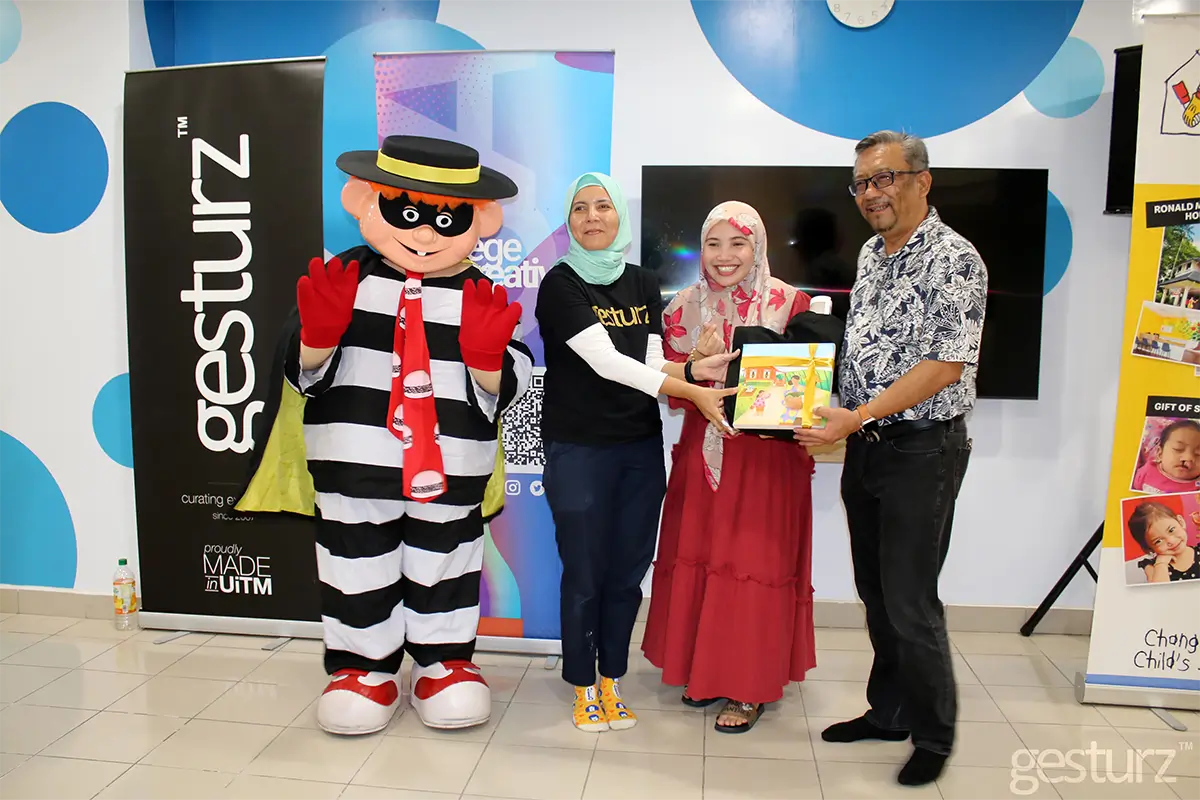 Event showcasing creativity with a mascot, participants from Gesturz, and a Nippon Paint branded gift presentation. The image features individuals celebrating a collaborative initiative in a vibrant setting.