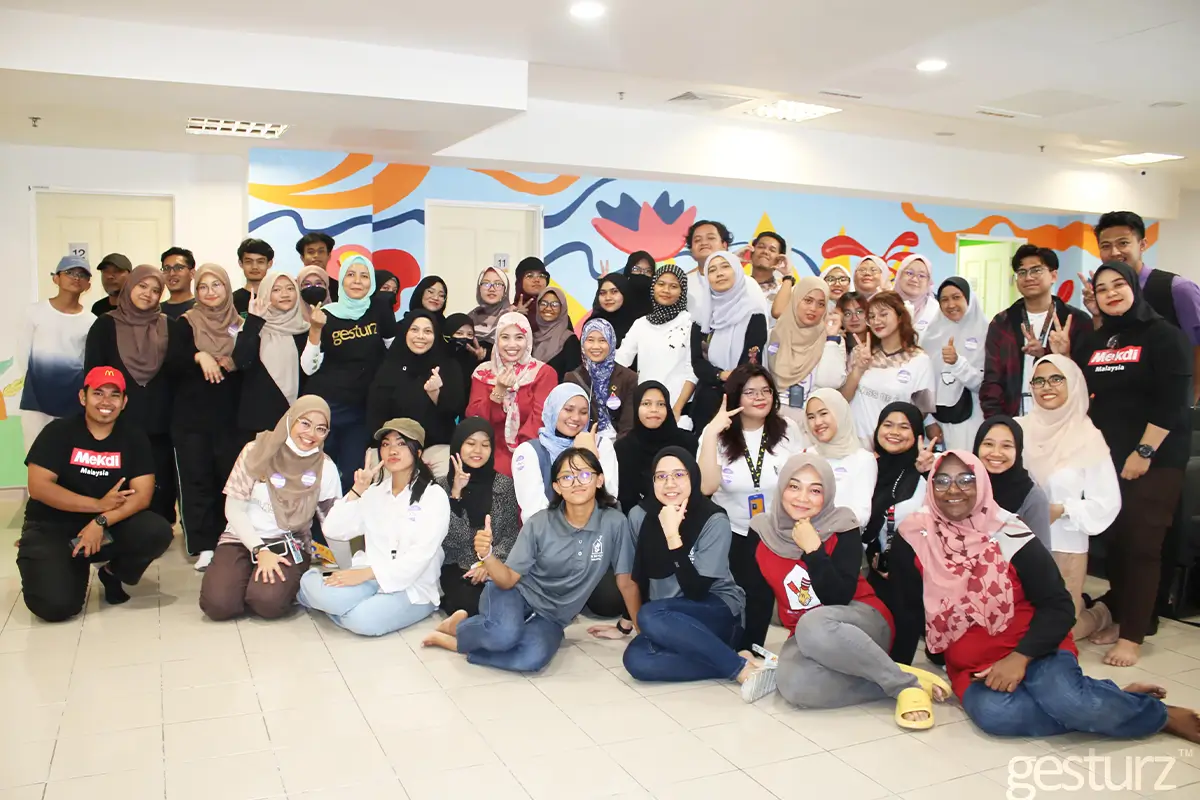 Group photo of a diverse gathering of individuals posing together in a well-lit room featuring a colorful mural. The event highlights community engagement and collaboration, showcasing the vibrant atmosphere enhanced by Nippon Paint products in the background.