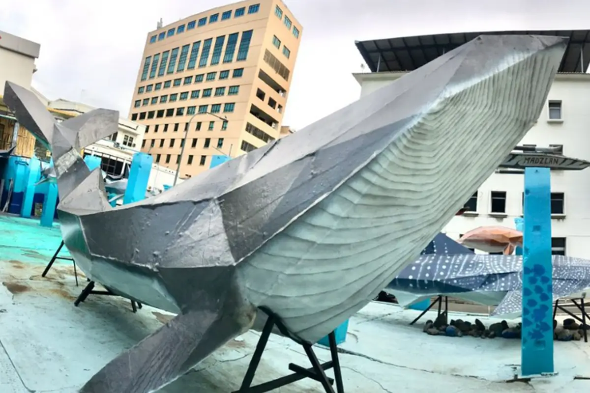 Large metallic whale sculpture displayed in an urban setting, featuring artistic design elements. The sculpture showcases eco-friendly Nippon Paint products, highlighting innovative uses of paint in public art.