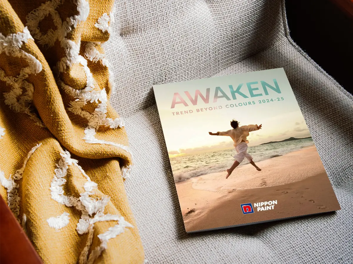 Nippon Paint's "Awaken" trend guide for 2024-25 displayed on a cozy, textured surface, accompanied by a soft yellow blanket, highlighting vibrant color inspirations for home decor.