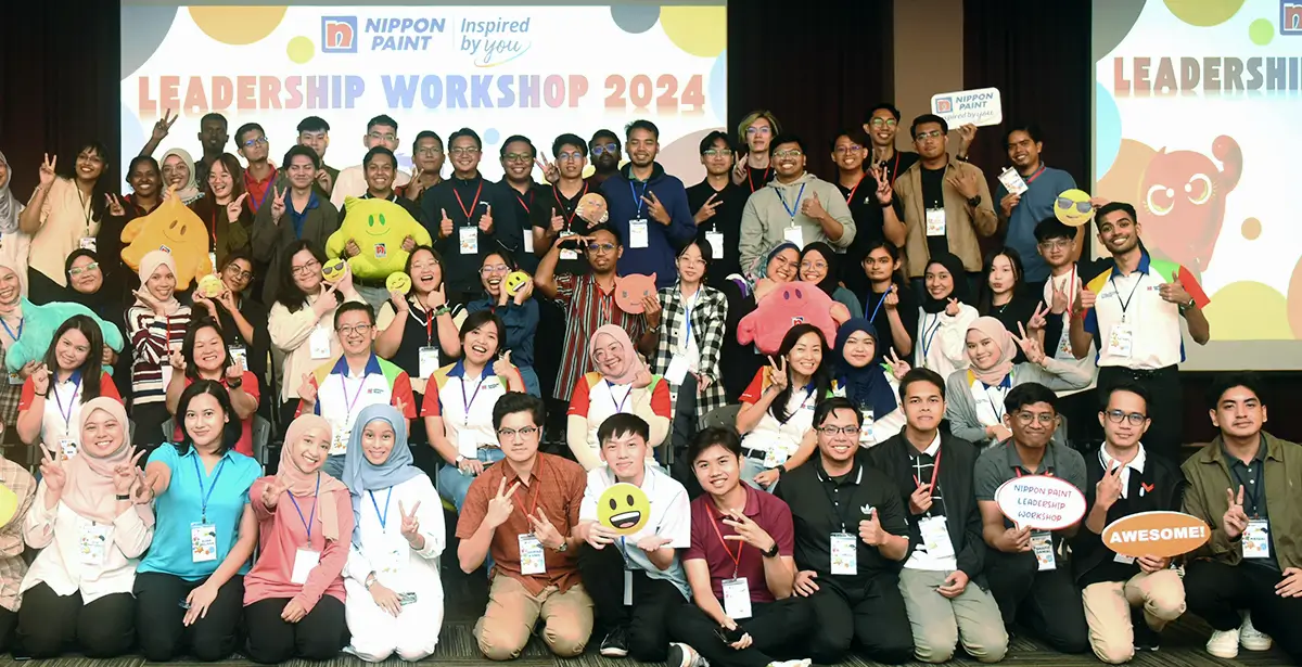 Group photo of participants at the Nippon Paint Leadership Workshop 2024, showcasing diverse individuals engaged in teamwork and learning, with colorful props and a vibrant backdrop emphasizing collaboration and leadership development.