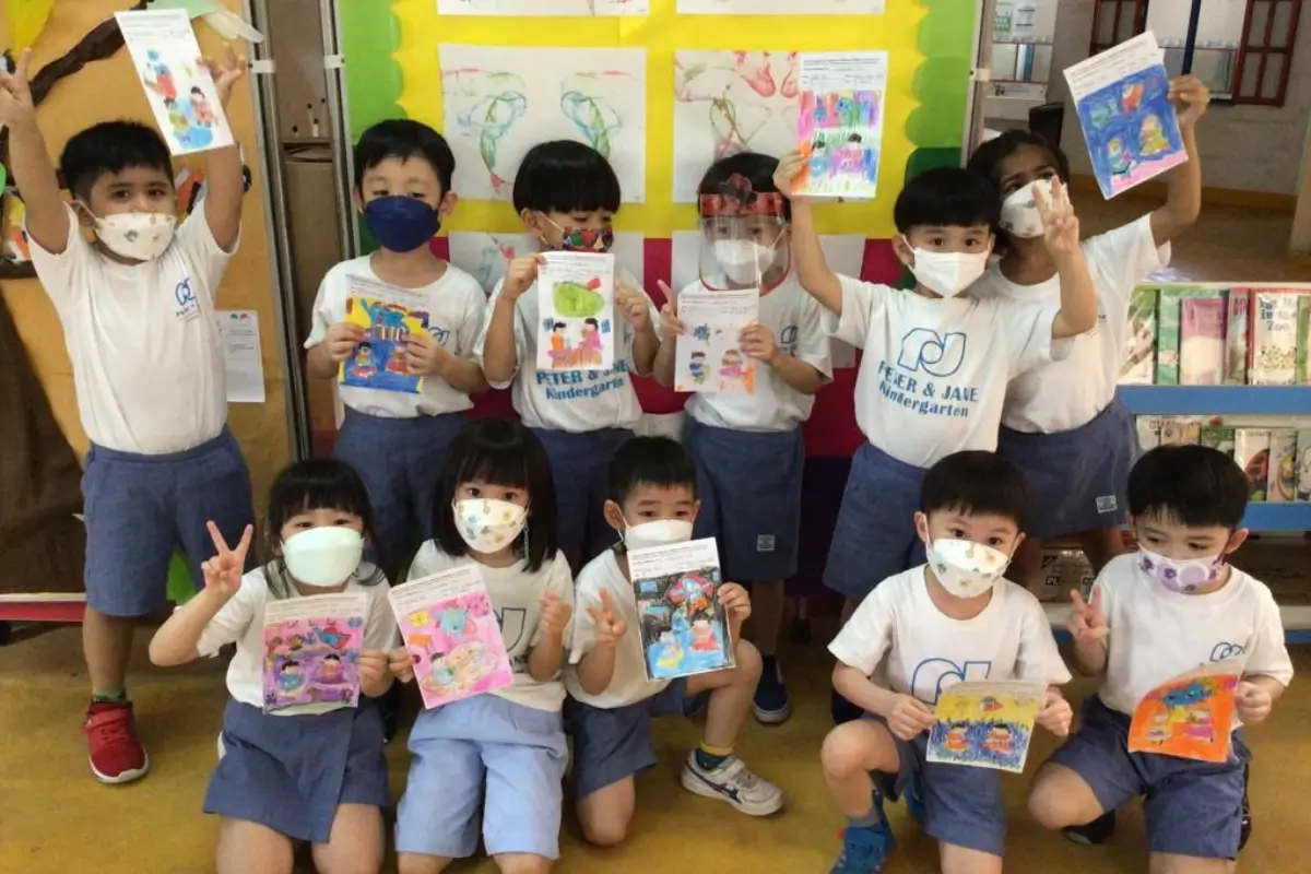 Children at Peter & Jae Kindergarten proudly displaying their colorful artwork, created using Nippon Paint products, in a vibrant classroom setting.