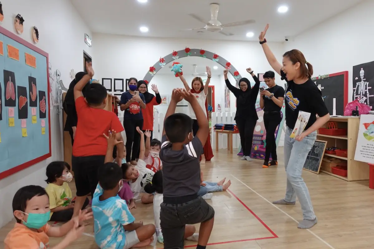 Children participating in an engaging classroom activity led by a teacher, with colorful Nippon Paint-branded educational materials displayed on the walls, fostering a vibrant learning environment.